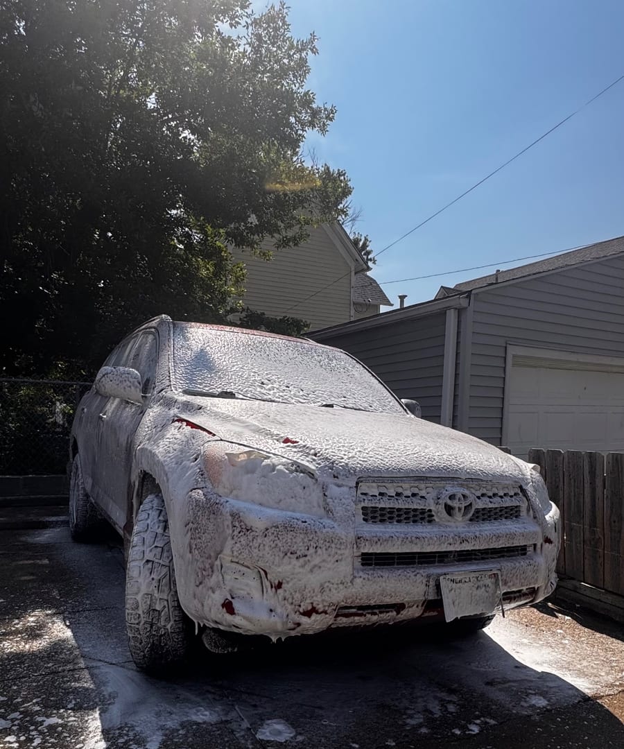 Mid-wash, a red RAV4 buried in foam during the decontamination wash